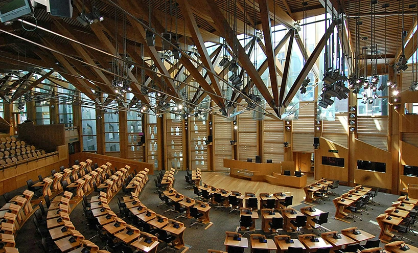 Interior view of the Scottish Parliament debating chamber, showcasing its modern design and semi-circular seating arrangement.