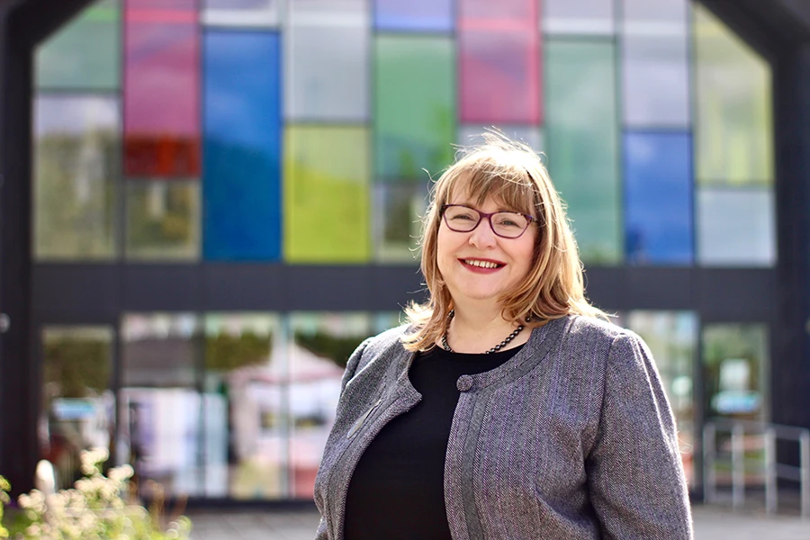 Clare Adamson MSP visiting Newmains Community Trust (NCT) in her constituency Clare Adamson MSP standing outside Newmains Community Trust (NCT) building with colourful glass panels in the background