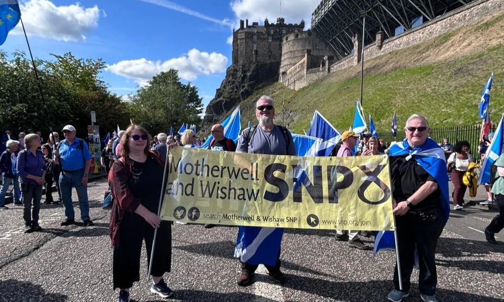 Clare Adamson MSP marching with constituents behind a “Motherwell and Wishaw SNP” banner near Edinburgh Castle.