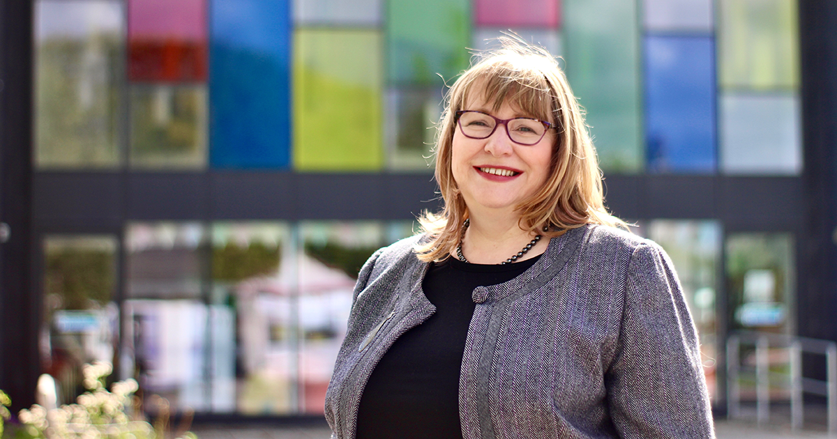 Clare Adamson MSP standing outside Newmains Community Trust (NCT) building with colourful glass panels in the background